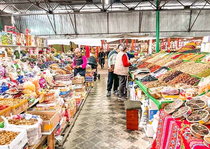 Outdoor market scene in a Kyrgyzstan bazaar with colorful displays of vegetables and grains